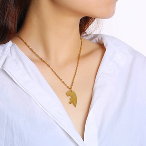 Detailed view of a gold-tone half-heart puzzle pendant necklace worn by a female model