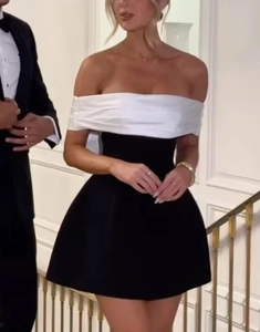 Detail of a chic black and white contrast off-shoulder mini dress worn by a model