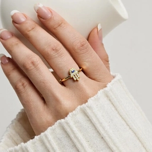Golden Hamsa hand ring with blue evil eye and sparkling zircons worn by a female model