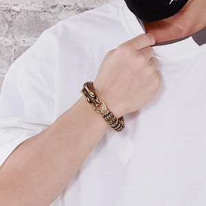 Detailed view of men's gold dragon scale link bracelet worn on wrist with dragon head clasp