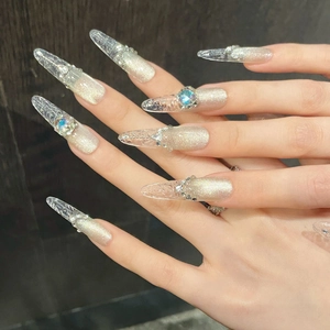 Makroansicht von Stiletto-Nägeln mit funkelnden Strasssteinen und Champagner-Katzenaugen-Glitzer