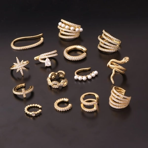 Set of 13 gold ear cuffs with cubic zirconia and pearls on black background