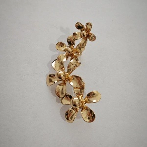 Detailopname van gouden crawler-oorbel met vier bloemmotieven in gebogen vorm