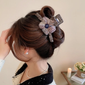 Detailed side view of knitted flower hair claw clip on model in warm home setting