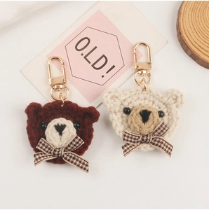 Detail of handcrafted woven bear keychains in brown and beige with plaid bow accents