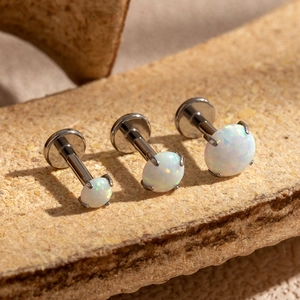 Macro shot of three stainless steel tragus studs with colorful synthetic opal inlays