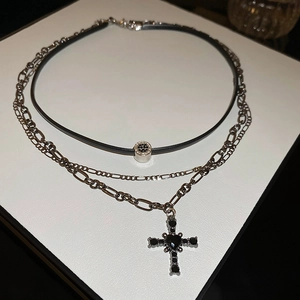 Dettaglio di una collana gotica a due strati con catena Figaro e pendente a croce nera