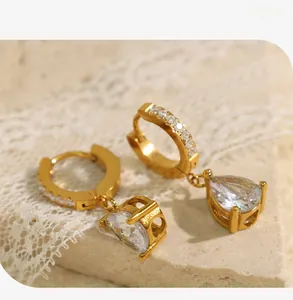Vue détaillée des boucles d'oreilles huggies dorées avec zircon goutte sur dentelle