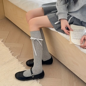 Detail of grey calf socks with white ribbon bows and vertical ribbed knit texture