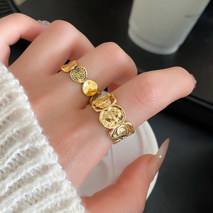 Detailansicht goldener asymmetrischer Ringe mit geprägter Rose und Rindenstruktur