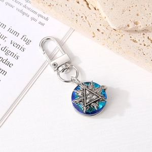 Detail of silver metal evil eye keychain with blue iridescent crystal charm on book