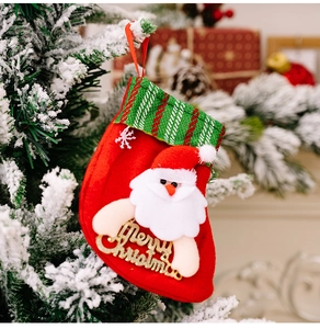 Close-up of a festive Christmas stocking with Santa Claus doll hanging on a snowy tree