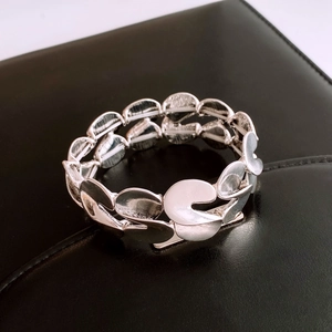 Detailed macro view of S-shaped twisted silver metal link bracelet on black leather surface