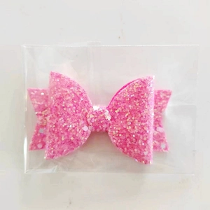 Glittery pink bow accessory for tumblers shown in transparent packaging on light background