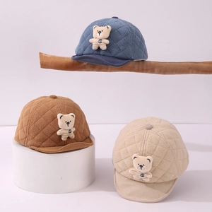 Detailed close-up of quilted winter baby hats with corduroy brims and plush bear accents