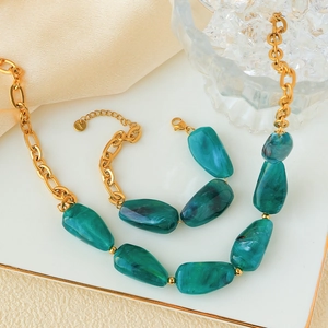 Detailed view of emerald marble stones and heavy gold stainless steel chain links