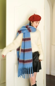 Detail of blue and reddish-brown striped scarf with thick fringed tassels and soft texture