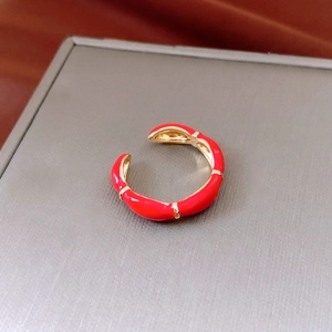 Macro shot of 14K gold plated open ring with red enamel and vertical gold stripe details