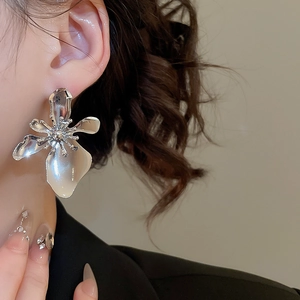 Detailed view of metallic flower earring with glossy petals and central stamen detail