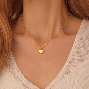 Close-up of heart bow pendant necklace with Love engraving on golden 18K titanium steel