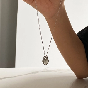 Detail of silver heart pendant necklace with cat-eye stone and toggle clasp closure
