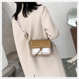 Chic color-block crossbody bag with wide embroidered strap worn by a model in a beige suit