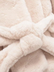 Detail of a creamy beige faux fur coat featuring a soft waist belt knot and plush texture