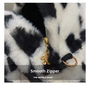 Close-up of a cow print plush backpack featuring a golden flower zipper and metal ring
