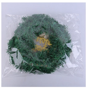 Close-up of a green PVC Christmas wreath with golden Merry Christmas text in packaging
