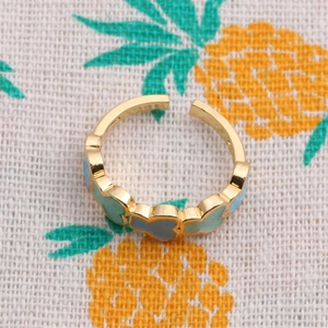Adjustable gold bear ring with blue and green enamel details on pineapple linen background