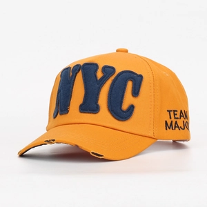 Dettaglio ravvicinato di un cappellino da baseball arancione con scritta NYC applicata blu