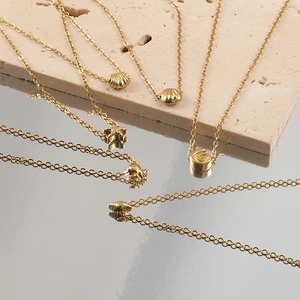 Golden stainless steel beach necklaces with starfish and shell pendants on stone