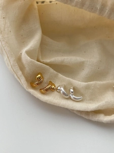 Detail of layered gold and silver hoop earrings with bead accents on linen fabric