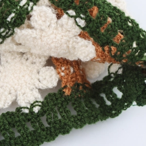 Detailed view of crochet knit tank top with patchwork patterns in green and beige