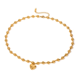 Macro shot of polished heart pendant and beaded gold stainless steel chain necklace