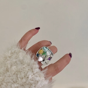 Detailed close-up of a vintage handmade silver ring featuring colorful stones and pearls