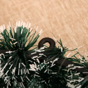 Macro view of green and white Christmas wreath foliage with black hanging ring detail