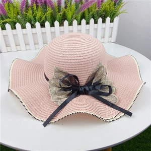 Detail of pink straw sun hat featuring wavy brim with contrast stitching and lace floral bow