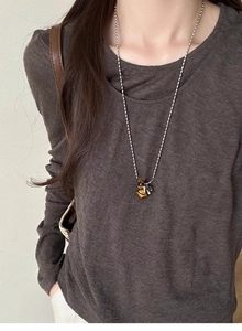 Detail of tiger eye planet pendant necklace worn by model on a dark brown top