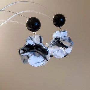 Détail de pétales de fleurs en résine marbrée sur des boucles d'oreilles pendantes