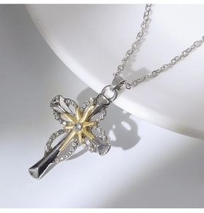 Close-up of two-tone cross pendant with gold starburst and crystal on ceramic plate