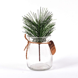 Detail of artificial pine branches in clear glass vase with decorative hemp rope and tag