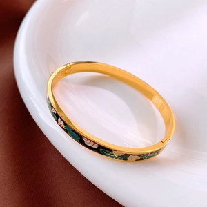 Détail d'un bracelet vintage doré avec motifs floraux en émail sur porcelaine blanche