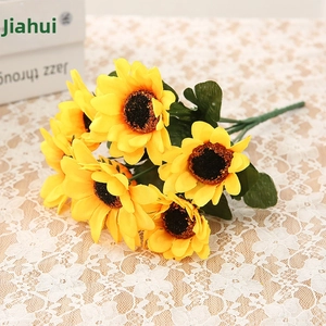 Detailed view of yellow artificial sunflowers with fabric petals on a white lace tablecloth