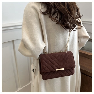 Detail of dark brown suede shoulder bag with V-quilt pattern and gold chain strap