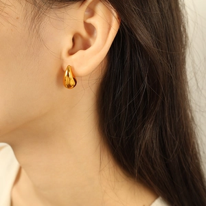 Polished 18K gold plated titanium steel teardrop earrings worn by a female model