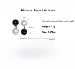 Macro shot of geometric black and white faux pearl earrings with copper gold-tone bar