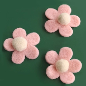 Three handmade pink wool felt flower ornaments for Christmas tree decor on green background
