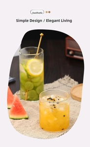 Detalle de vasos de borosilicato con textura estriada con té de frutas y agitador dorado