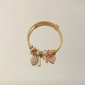 Detail of adjustable gold wire bracelet with pink enamel heart and pearl charm